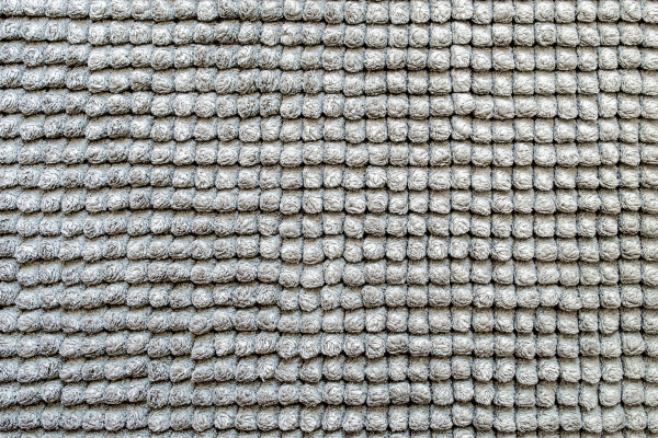 A detailed texture view of a loop-pile carpet in a neutral gray shade, showcasing its intricate design.