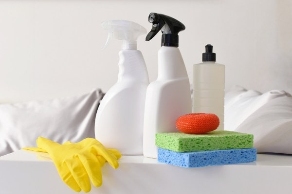 Cleaning supplies with sponges, spray bottles, and gloves