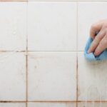 a person cleaning dirty shower tiles