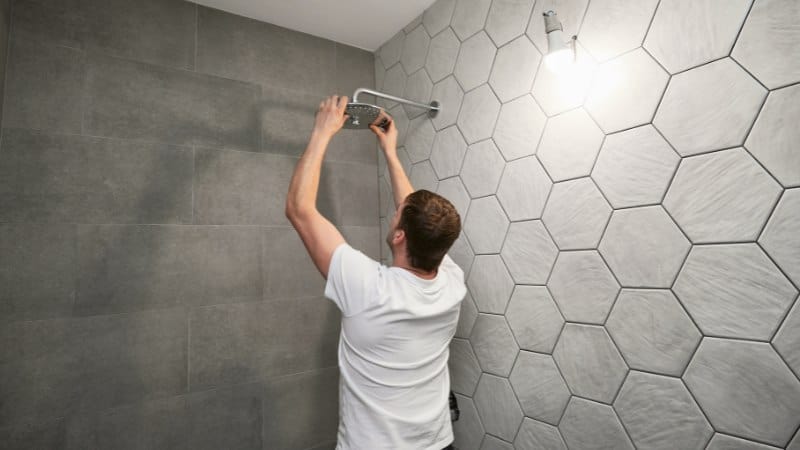 a person inspecting a shower head in neat and clean bathroom