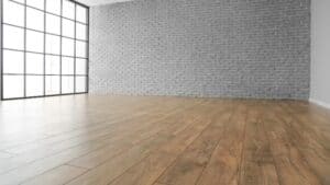 Empty room with laminate floor and brick wall.