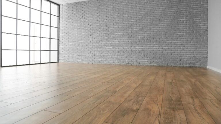 Empty room with laminate floor and brick wall.