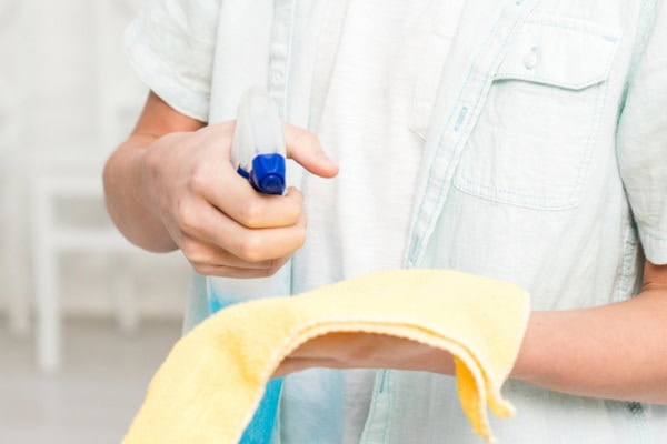 a man spraying glass cleaner on a soft cloth