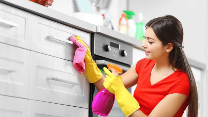 a woman in red dress cleaning kitchen cabinet