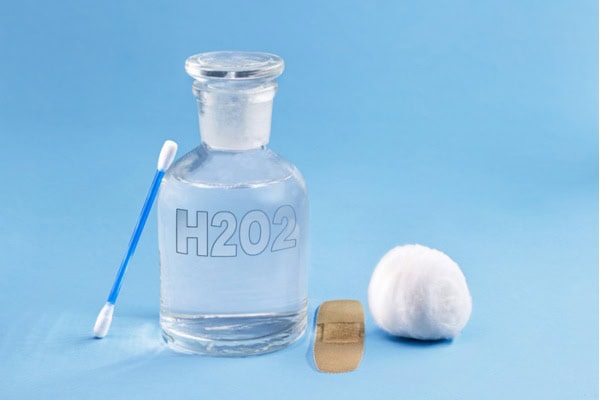 bottle of hydrogen peroxide with cotton wipe in blue background