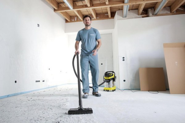 Professional cleaner vacuuming dust and debris from a renovated floor.