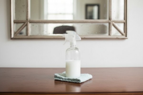 Spray bottle with homemade cornstarch cleaner placed on cloth.
