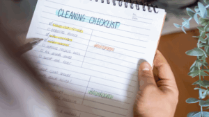 A person reviews a handwritten cleaning checklist with tasks highlighted in different colors.