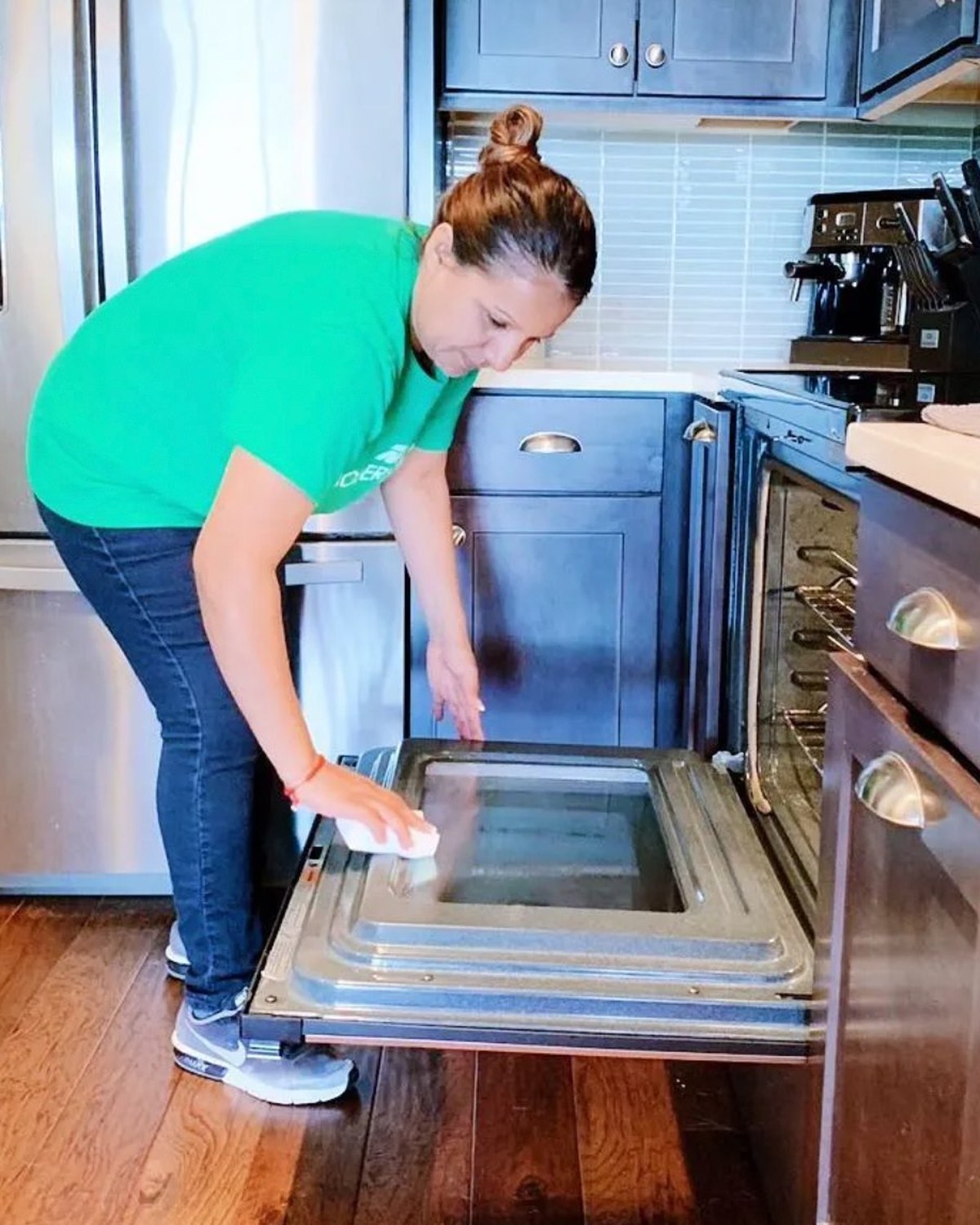 A Modern Maids cleaner scrubbing the inside of an oven door during a move-out clean